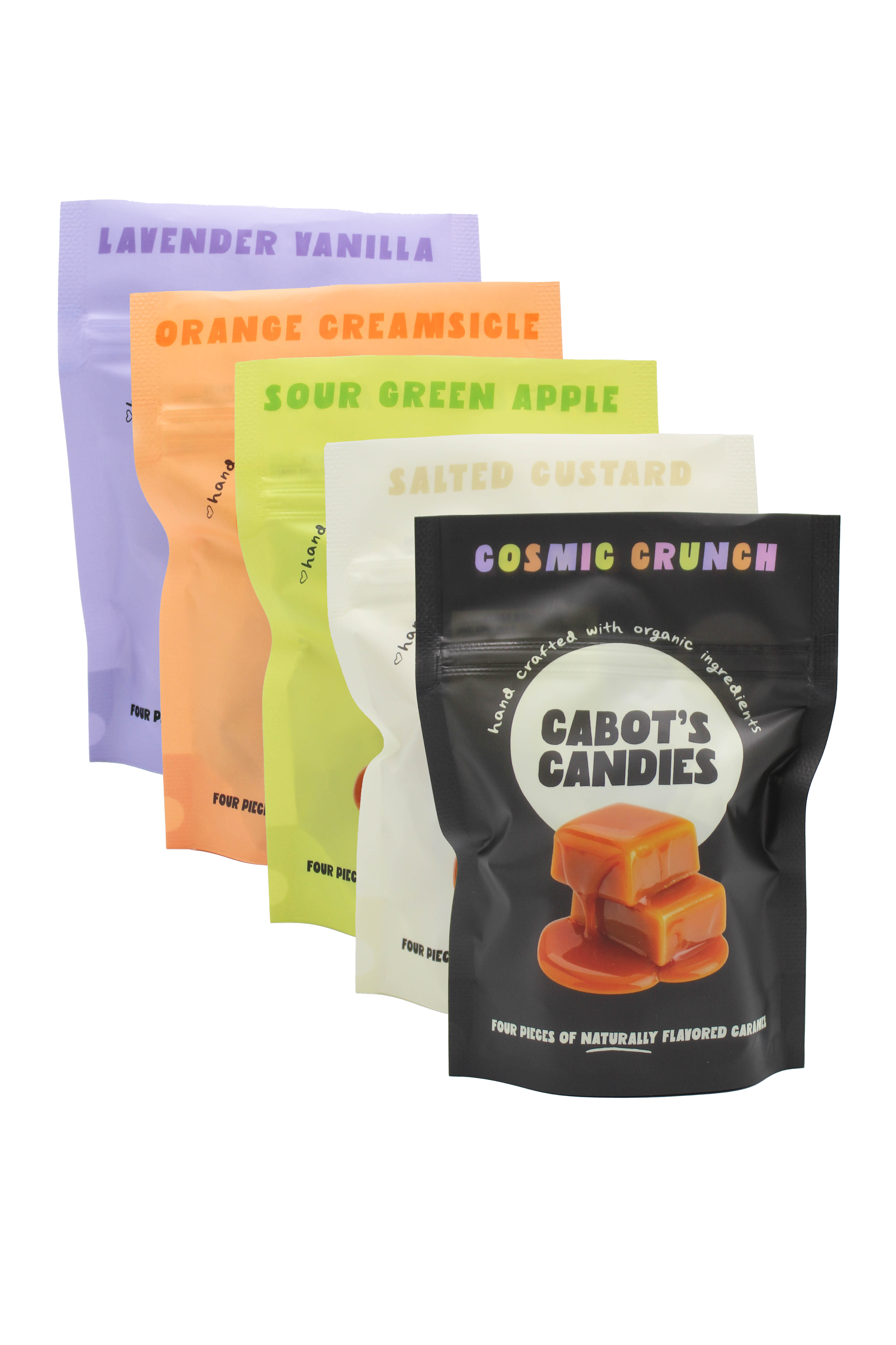 Five stand-up candy pouches fanned out on a white background, each in a different flavor color: lavender vanilla, orange creamsicle, sour green apple, salted custard, and cosmic crunch. The front pouch is black with a caramel candy photo and the brand name Cabot's Candies.
