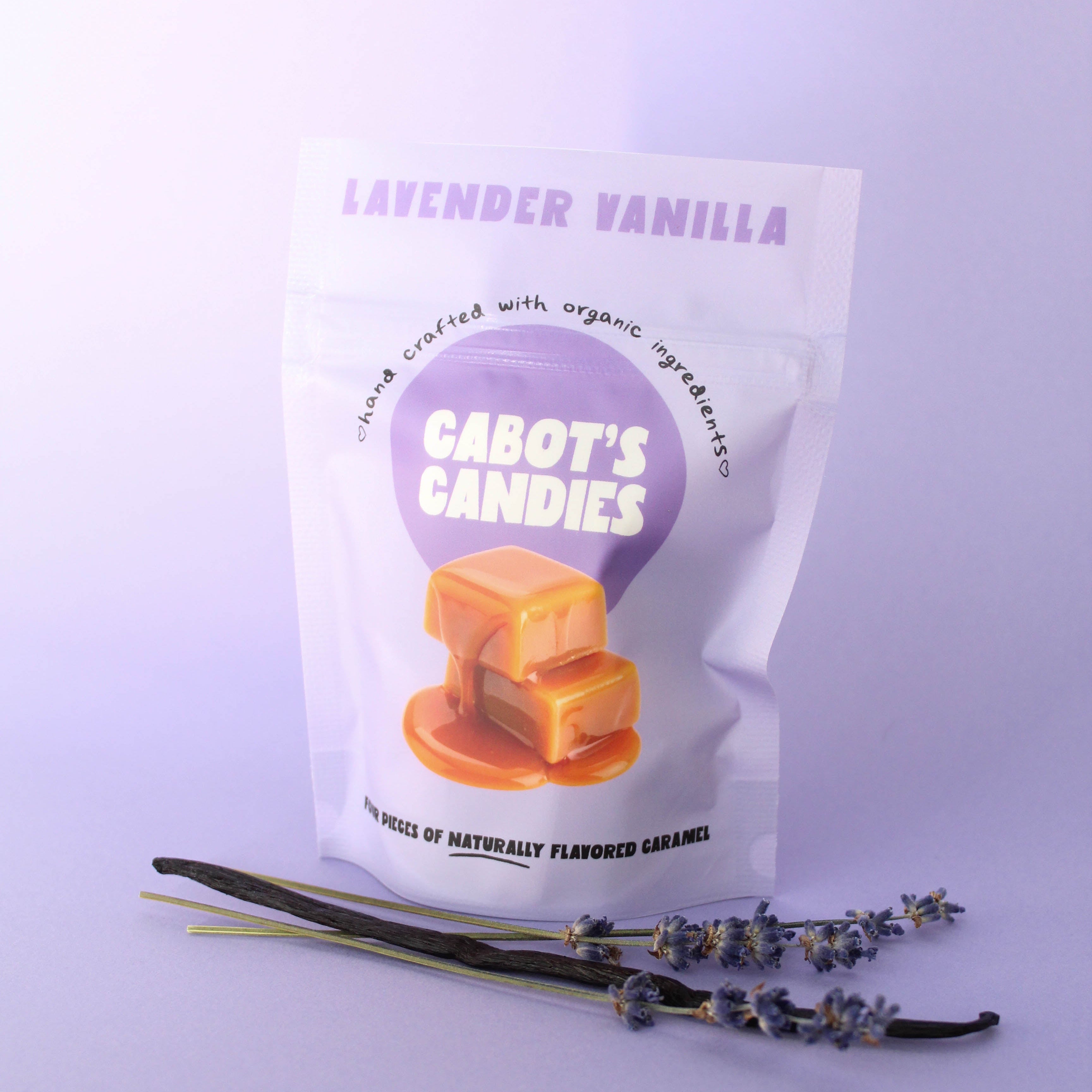 A stand-up pouch of Cabot's Candies lavender vanilla caramel candies, displayed with vanilla beans and lavender sprigs on a light lavender background.