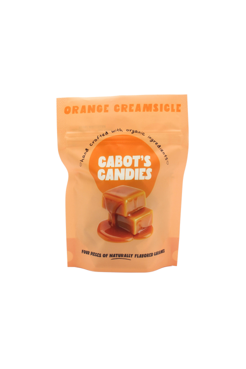 An orange stand-up pouch of Cabot's Candies Orange Creamsicle candy, featuring a graphic of two caramel candies on a white background.